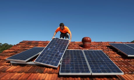 A solar system installer adjusts new solar panels on the roof of a house