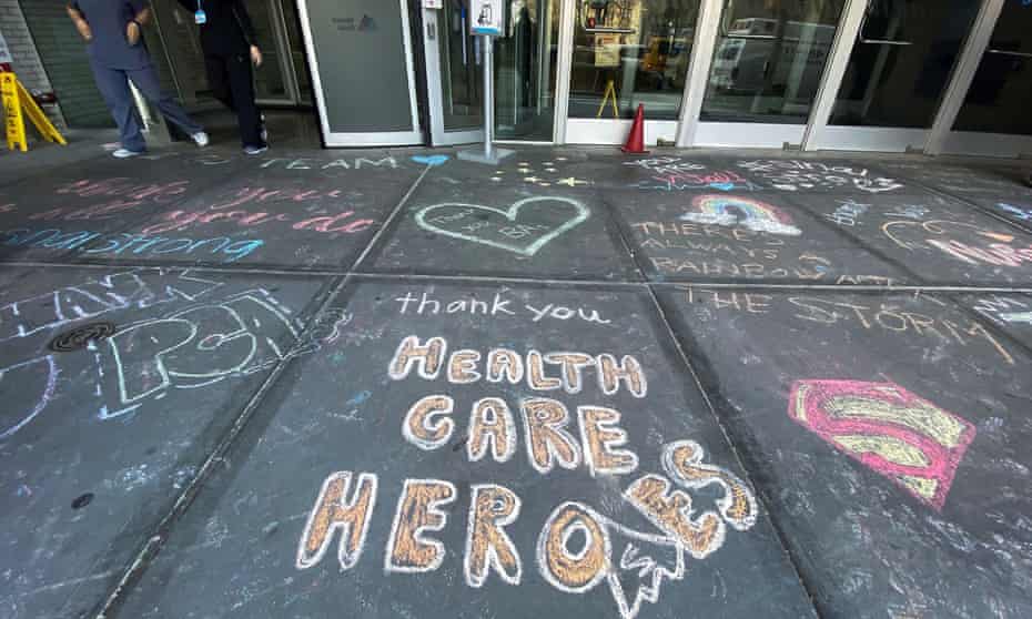 Healthcare workers exit Mount Sinai hospital past messages of thanks written on the sidewalk in New York City.