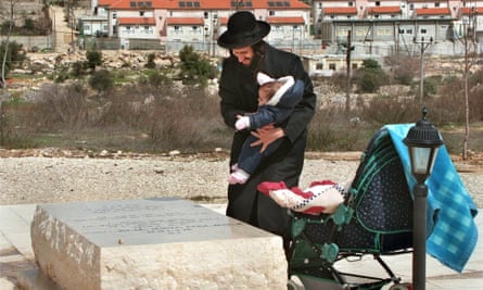 An ultra-Orthodox Jew and his baby visit the grave of Baruch Goldstein who killed 29 Palestinian worshippers in Hebron.