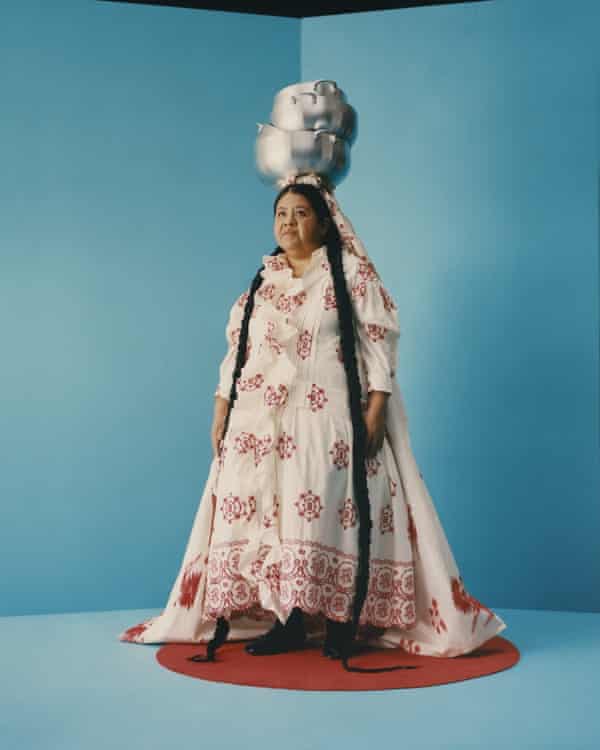 woman wears white dress and large headwear on blue background