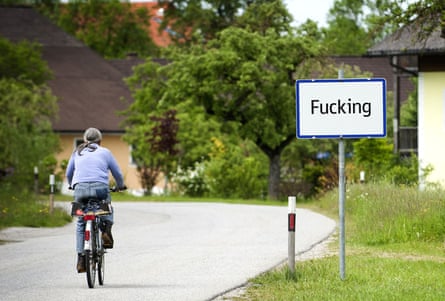 A man cycling past a road sign for Fucking in Austria