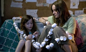 Jacob Tremblay and Brie Larson as a mother and son, sitting close together stringing egg shell halves together, in Room.