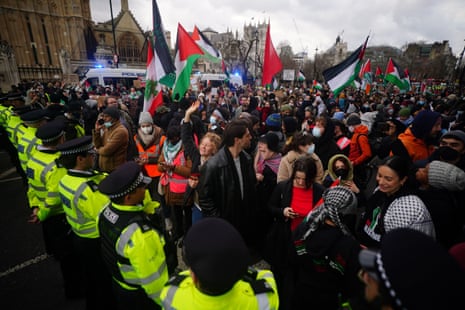 Police officers form a cordon in front of pro-Palestine protesters during a demonstration outside the Houses of Parliament.