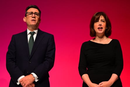 Burnham and Powell standing and singing, each with their hand folded in front of them