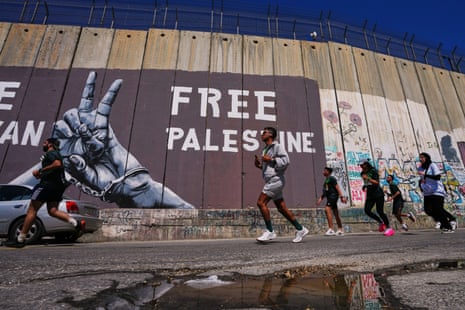 Runners pass by Israel's separation wall as they compete in the Palestine Marathon in the occupied West Bank city of Bethlehem.