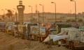 Queue of loaded lorries with red skies behind