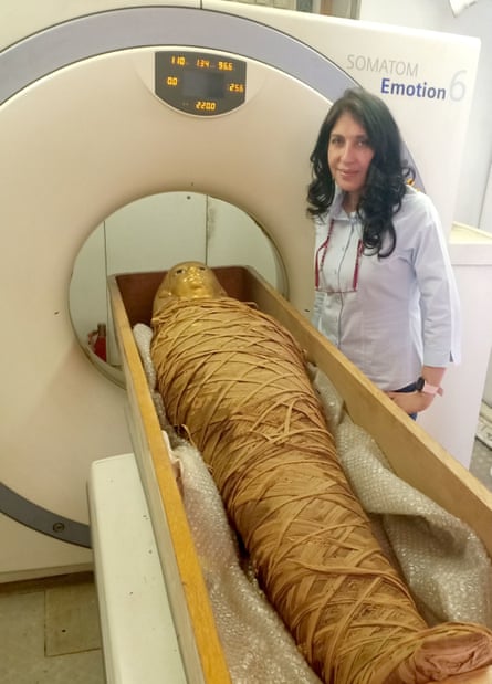 Dr Sahar Saleem standing beside a CT scanner machine with the mummy