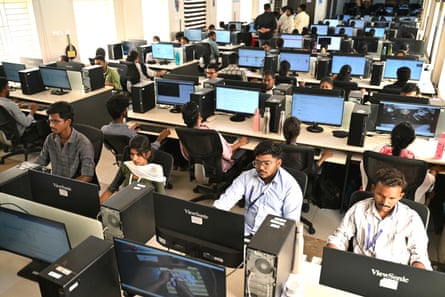 A large room full of people sitting in front of computer screens