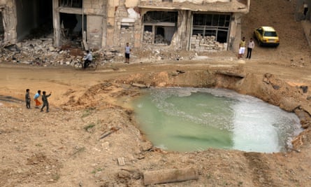 People inspect a water-filled hole at the site of an airstrike on the rebel-held Tariq al-Bab neighbourhood of Aleppo.