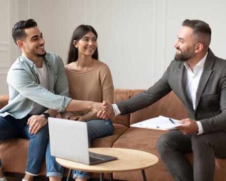 A couple shake hands with a businessman after signing a contract