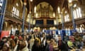 Crowds of people in an ornate hall, visiting various stalls