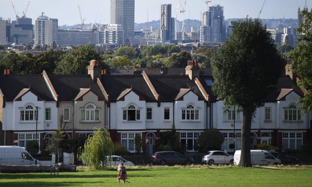 A woman walks by a row of houses in London