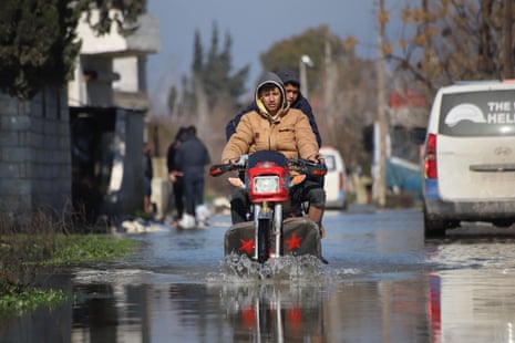 Syrians ride a motorcycle in a flooded area after the collapse of a dam on the Orontes (Assi) river near al-Tulul village in Salqin, in Syria's rebel-held Idlib province, near the border with Turkey.