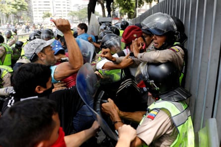 Demonstrators and security forces scuffle against a fence