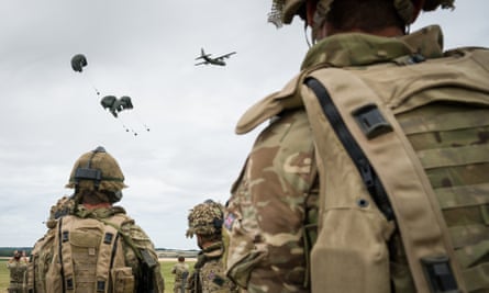 A military exercise on Salisbury Plains in July 2020 near Warminster, England, soldiers seen from the rear observe an air drop
