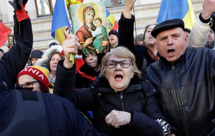 Supporters of Calin Georgescu (not pictured) wave flags and shout slogans outside the Bucharest Court