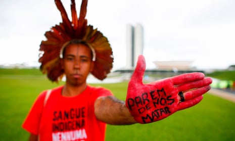 A protester shows a sign on his hand that reads ‘Stop killing us’, during a demonstration this year against a bill that would open lands to mining in Brazil.
