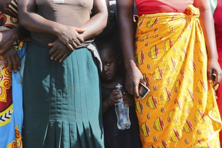 A child stands between women waiting to receive food aid, in Mudzi, Zimbabwe