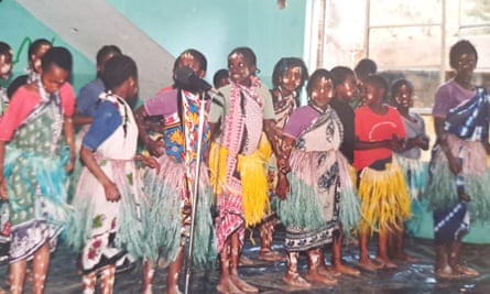 A group of young African girls in traditional dress perform at school