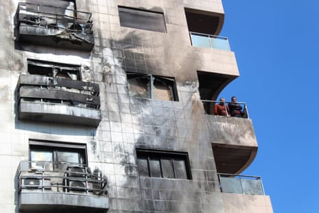 Men stand on a balcony of a damaged building in the Kafr Sousa district, Damascus, Syria.