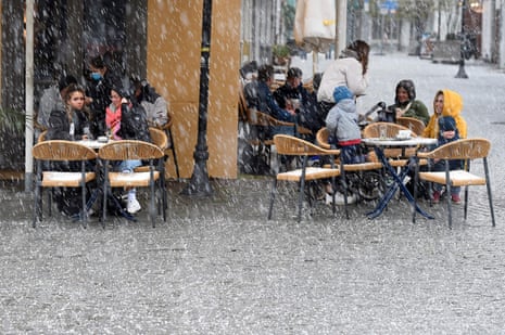 Guests sit outside at a cafe during a sleet shower in Saarbruecken, western Germany, on 6 April, 2021. Germans in the tiny border state of Saarland returned to cafes, cinemas and cultural venues on 6 April, even as the rest of the country faces tighter coronavirus restrictions amid rising case numbers.