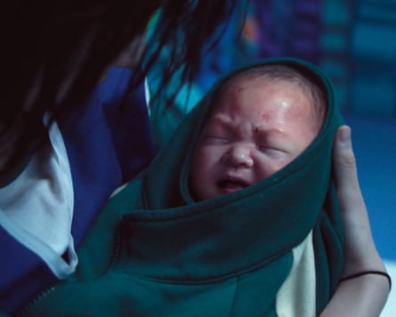 A baby is cradled in a green and white jumper