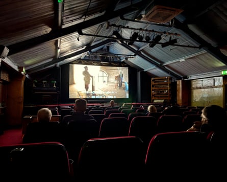 People sitting inside an old cinema watching a film