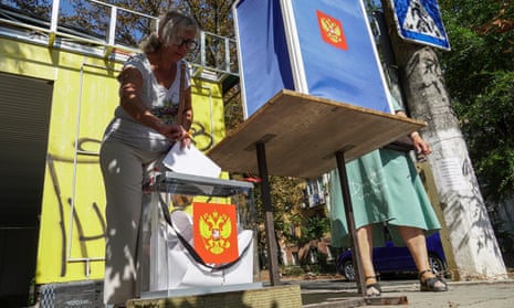 A woman casts her ballot at a mobile polling station with the coat of arms of Russia during early voting for the local elections in Mariupol, Russian-controlled Ukraine, 31 August 2023.