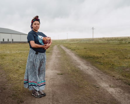 A woman wearing a skirt holding a bison heart outside.