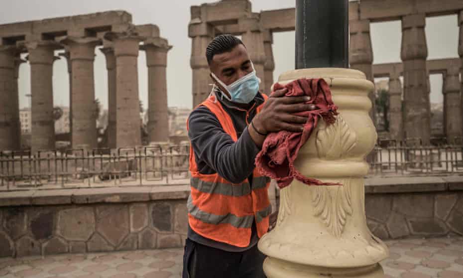 A municipality worker cleans lamp posts amid a sandstorm and coronavirus fears outside the Luxor Temple in Egypt’s southern city of Luxor on 12 March.