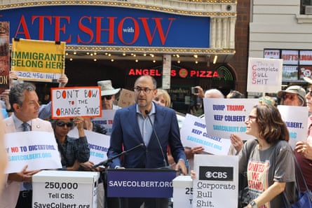 Man in suit speaks at lectern among crowd in front of marquee that says Late Show