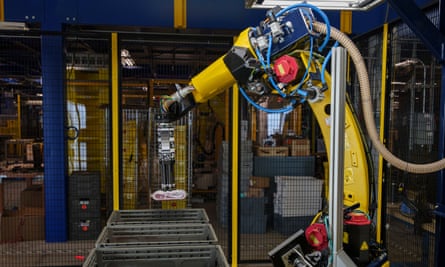 Yellow robotic arm putting a package in a box.