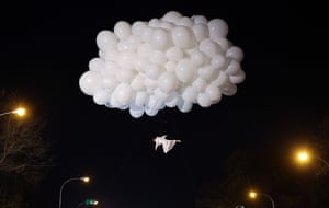 An acrobat appears to be suspended by floating balloons during a performance of the Three Kings epiphany parade in Madrid, Spain