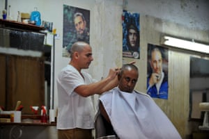 A barber works near posters of Castro and fellow Cuban revolutionary leader Che Guevara