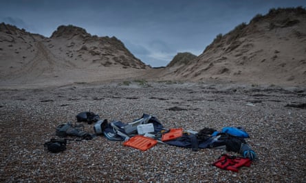 People’s belongings, along with a deflated dinghy, lifejacket and engines, lie on the beach