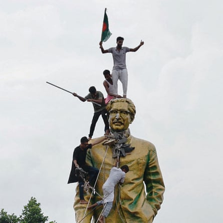 People with flags and stick climb a giant statue