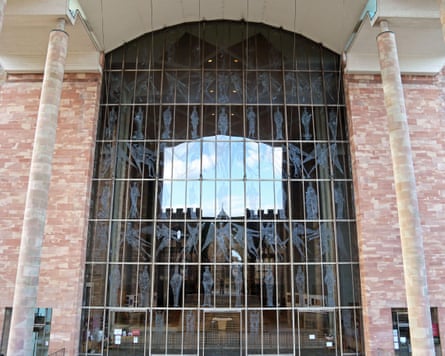 A huge arched window of panels featuring engravings of saints and angels