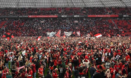 Bayer Leverkusen supporters flood the pitch at full-time as the title was confirmed.