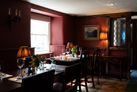 Tables laid inside a smart pub with dark red walls