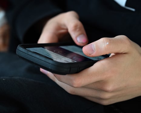 A young person uses their mobile phone to access social media