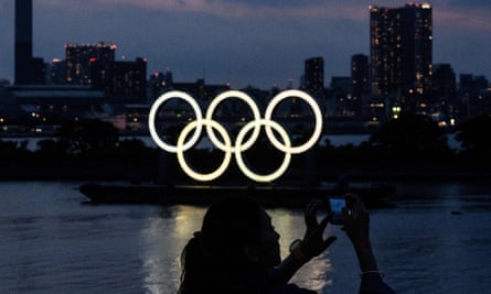 A woman takes pictures in front of the Olympic rings in Tokyo