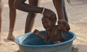 Guerline Augustin, 15, washes her eight-month-old daughter at a borderland encampment outside Anse-à-Pitres, Haiti.