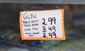 A rectangular white sign lined in orange with black hand-lettering reads: Goya, Peas & carrots/Green beans: 2.99, Green peas: 3.49, Whole kernel corn: 2.49
