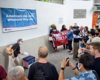 a woman drops a ballot in a box under a banner that reads 'Americans can vote wherever they are'