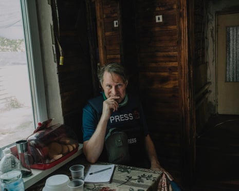Luke Harding wearing a press jacket sitting a table with a pen and paper in a house outside Pokrovsk in eastern Ukraine