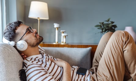 Side-view photo of a young man relaxing on the sofa at home with his eyes closed