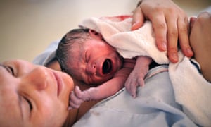 A newborn baby held by his mother moments after birth
