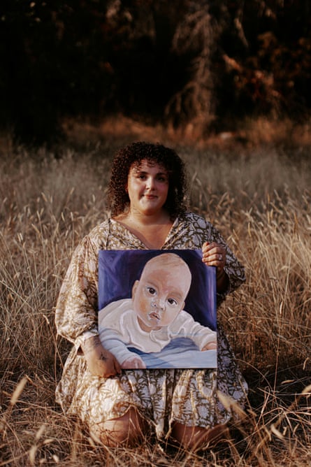 Alexandra Smith sits in a field with a painting of her son Aksel
