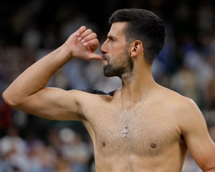 Novak Djokovic with shirt off and his thumb in his mouth