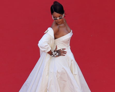 Rihanna wears a white ballgown with white sunglasses on the red carpet.
